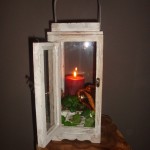 Kerststuk 10 : 15 Euro Lantaarn van hout en glas met deur en kaars.