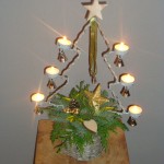 Kerststuk 3 : 12 Euro  Rond riet/tinnen bak met waxinelichthouder in de vorm van een kerstboom.