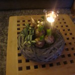 Kerststuk 2: 10 Euro  Grijze ronde mand met glazen waxinelichthouder.